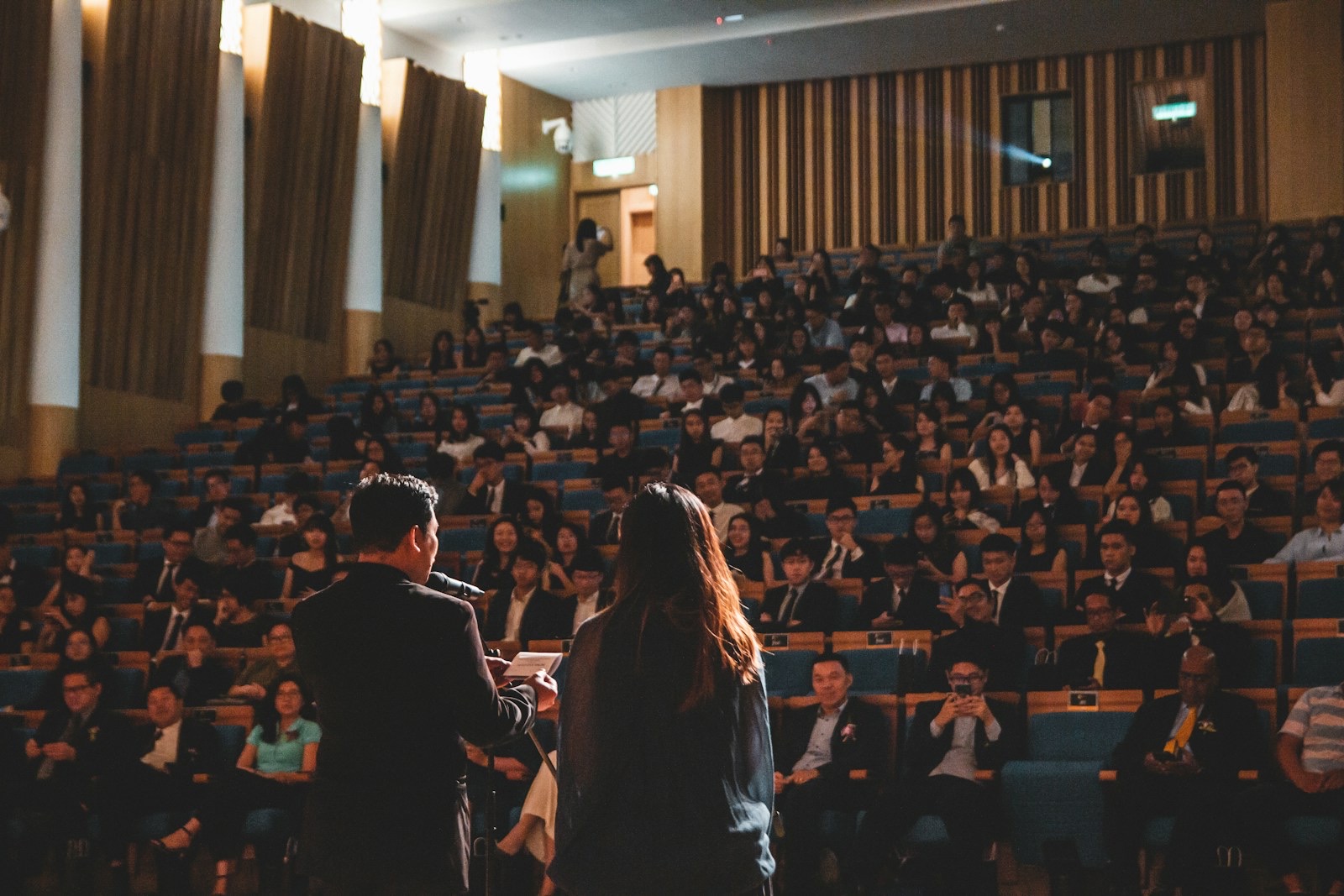A speaker with an interpreter beside him addressing a full auditorium