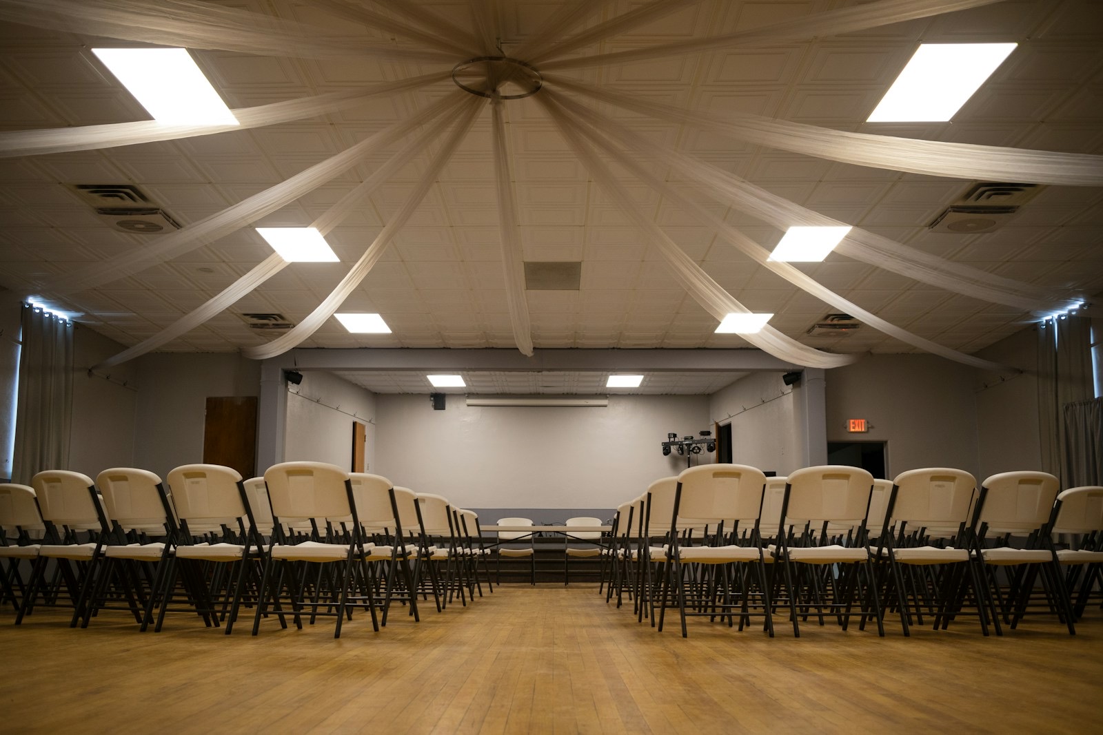 A church fellowship hall with rows of chairs set out under a draped ceiling